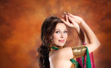Geleneksel bellydance bir kostümle renkli stüdyo arka plan üzerinde dans muhteşem bir kadın bellydancer.