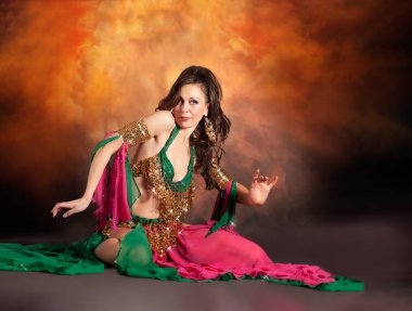 Geleneksel bellydance bir kostümle renkli stüdyo arka plan üzerinde dans muhteşem bir kadın bellydancer.