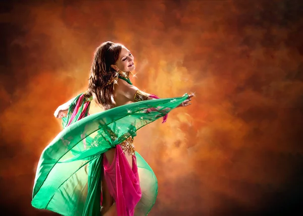 Gorgeous woman bellydancer dancing in traditional bellydance costume over colored studio background. — Stock Photo, Image