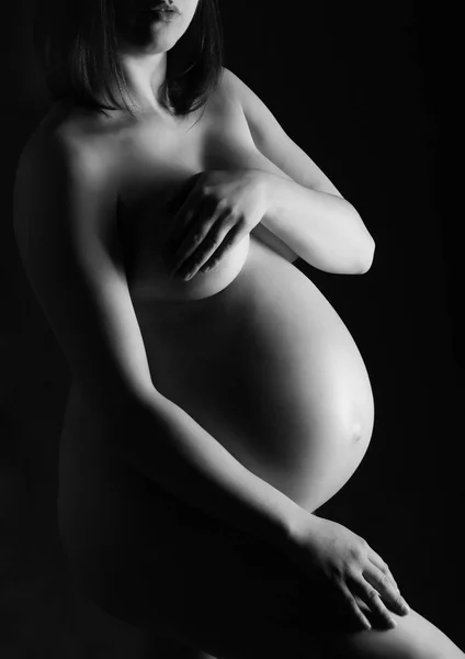 Pregnant woman, expectant mother on black background, monoshrome shoot. — Stock Photo, Image