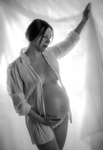 Těhotná žena, nedočkavý matka na bílém pozadí, zblízka na těhotné břicho, monolit. — Stock fotografie