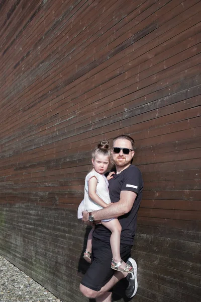 Joven padre guapo sosteniendo a su hija en sus brazos — Foto de Stock