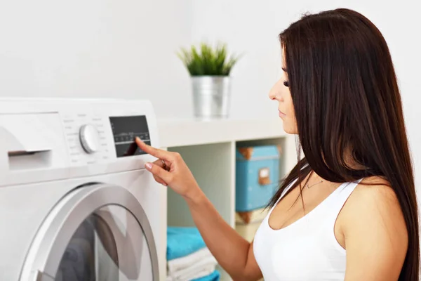 Retrato de ama de casa joven con lavandería al lado de la lavadora — Foto de Stock