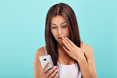 Mavi duvar arka plan karşı akıllı telefon kullanan kadın