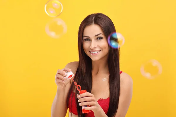 Woman with bubbles against yellow wall background — Stock Photo, Image