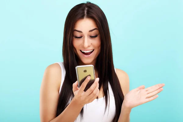 Frau benutzt Smartphone vor blauem Wand-Hintergrund — Stockfoto