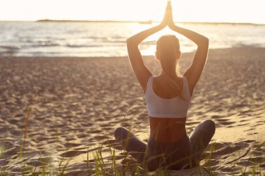 gün batımında sahilde Yoga uygulamak siluet genç kadın