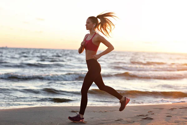 Mujer corriendo sola al atardecer en la playa —  Fotos de Stock