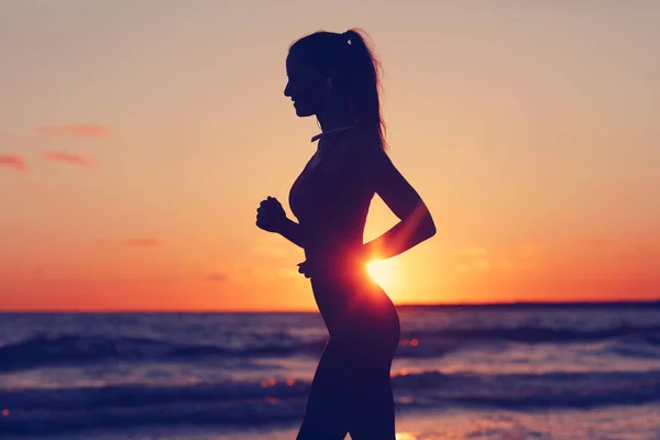 Žena běží sám na krásnou soumraku na pláži — Stock fotografie