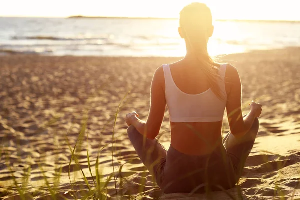 剪影年轻女子在日落时练瑜伽在海滩上 — 图库照片