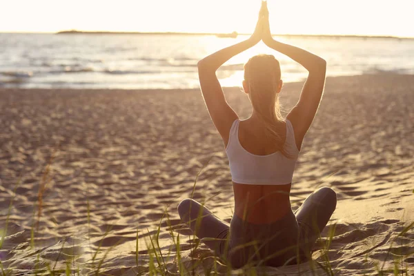 Silhouette junge Frau übt Yoga am Strand bei Sonnenuntergang — Stockfoto