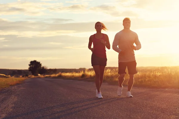 Jovem casal correndo nos suberbs após o pôr do sol — Fotografia de Stock