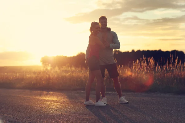 Ungt par jogging i suberbs efter solnedgången — Stockfoto