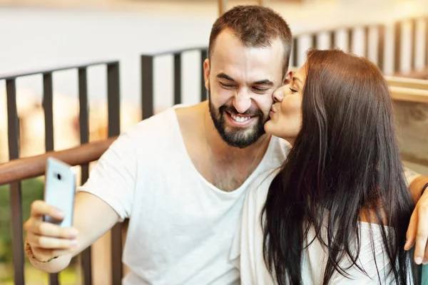 Romantyczna para widuje się w kawiarni i przy użyciu smartfona — Zdjęcie stockowe