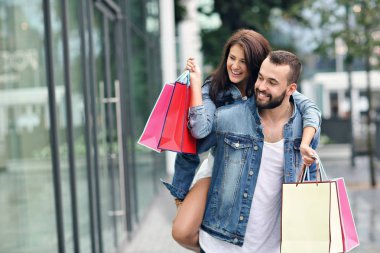 Alışveriş yaptıktan sonra alışveriş torbalarıyla mutlu bir çiftin portresi.