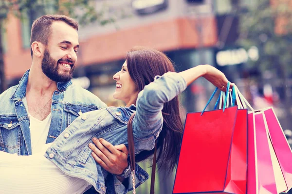 Retrato de casal feliz com sacos de compras depois de fazer compras na cidade — Fotografia de Stock