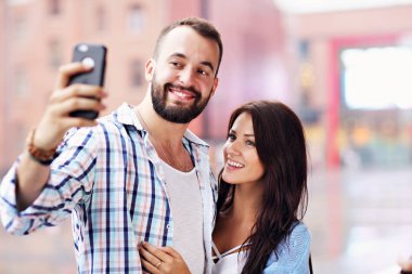 Mutlu çift Smartphone şehirde yağmurlu günde kullanarak.