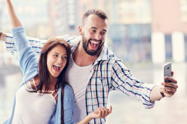 Mutlu çift Smartphone şehirde yağmurlu günde kullanarak.