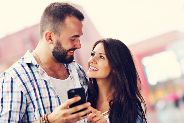 Pareja feliz usando teléfono inteligente en la ciudad en días lluviosos — Foto de Stock