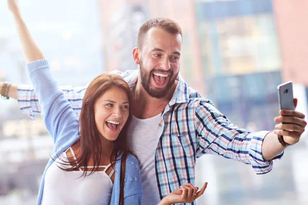 Happy couple using smartphone in city in rainy day — Stock Photo, Image
