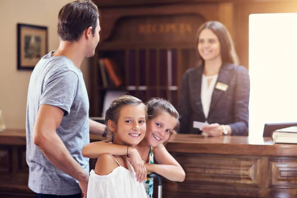 Happy family checking in hotel at reception desk — Stock Photo, Image