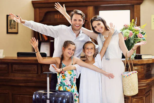 Happy family checking in hotel at reception desk — Stock Photo, Image