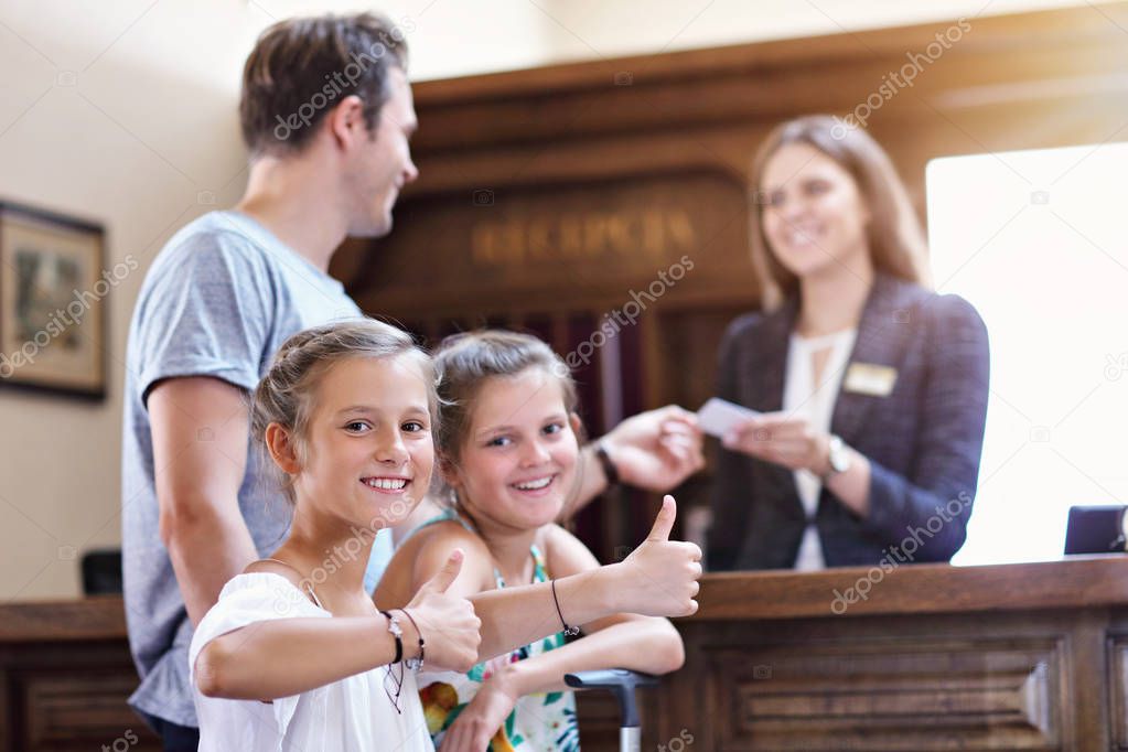 Happy family checking in hotel at reception desk