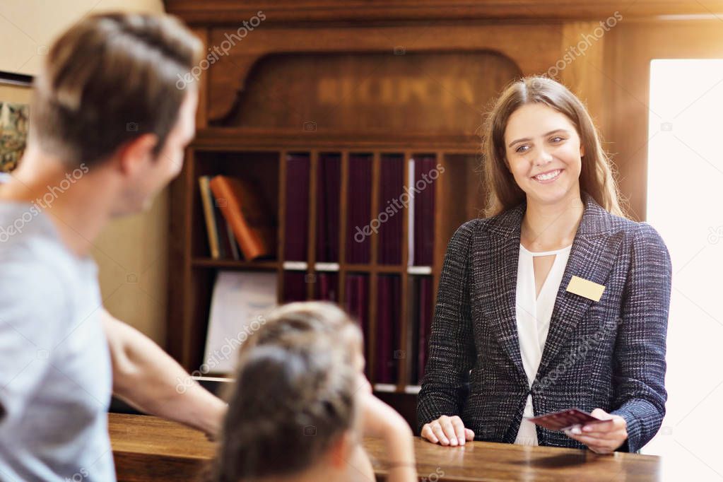 Happy family checking in hotel at reception desk