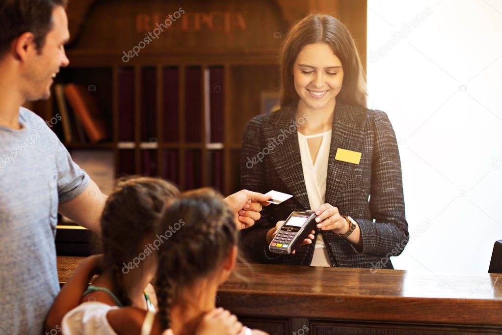 Happy family checking in hotel at reception desk