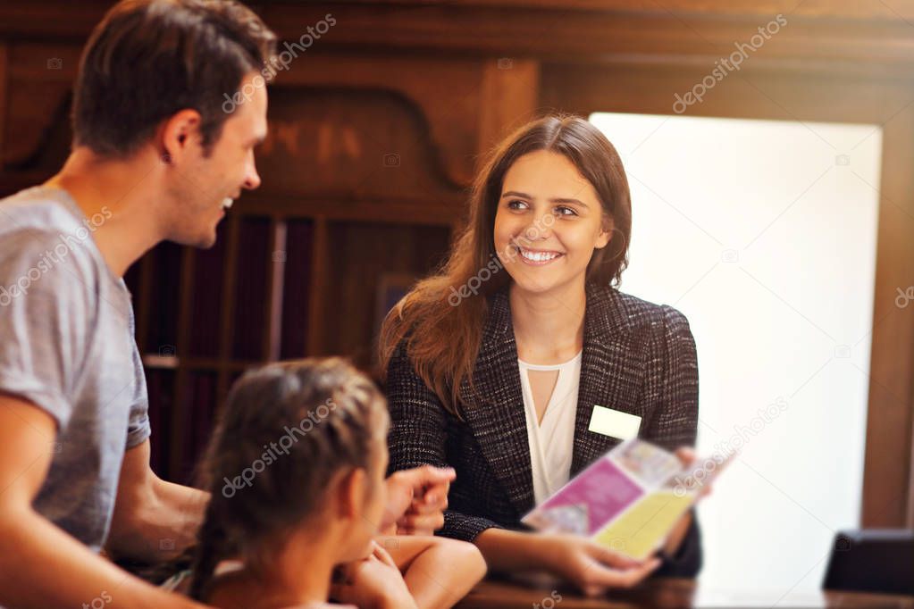 Happy family checking in hotel at reception desk