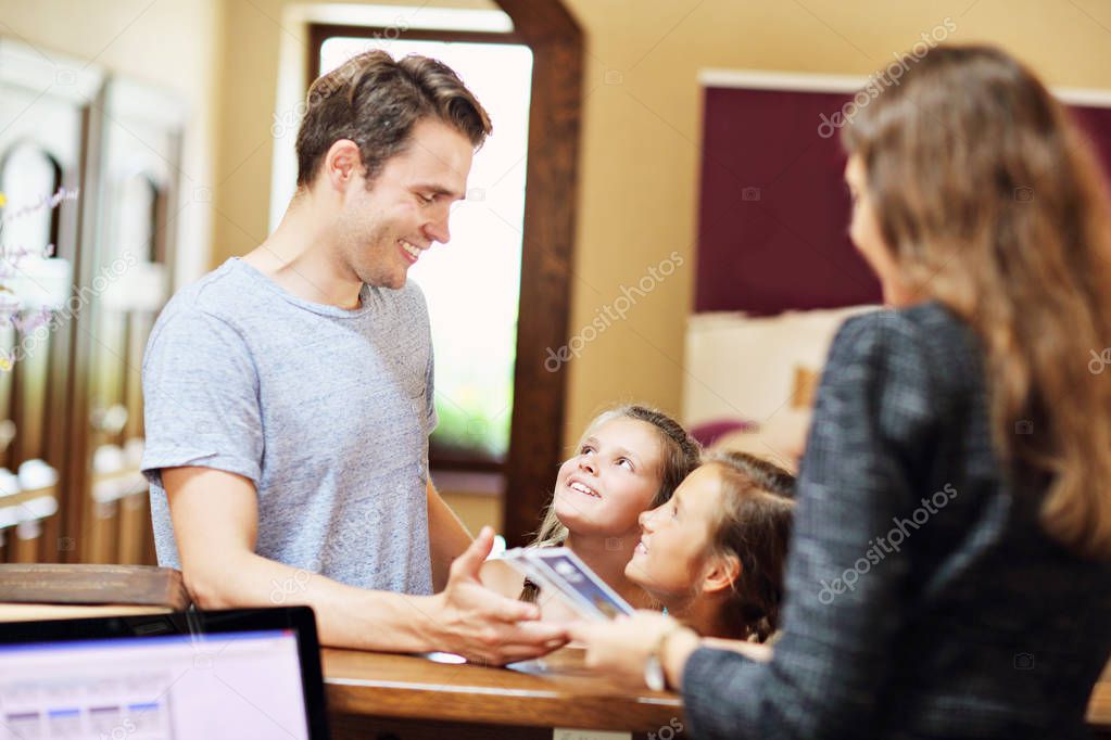 Happy family checking in hotel at reception desk