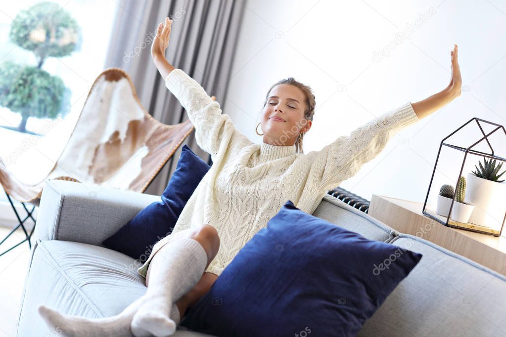 Adult woman wearing warm sweater resting at home one autumn day