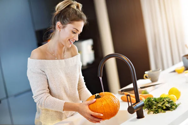 Mulher adulta lavando abóbora na cozinha para o Halloween — Fotografia de Stock