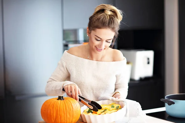 Erwachsene Frau in der Küche bereitet Kürbisgerichte für Halloween zu — Stockfoto