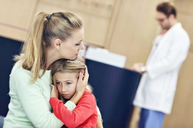 Küçük kız annesiyle birlikte iken bir doktor Danışma üzerinde ağlıyor