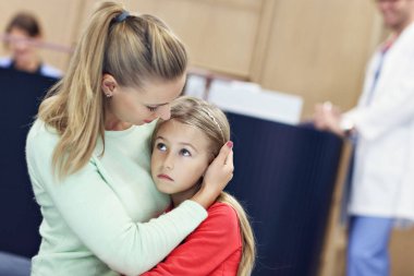 Küçük kız annesiyle birlikte iken bir doktor Danışma üzerinde ağlıyor