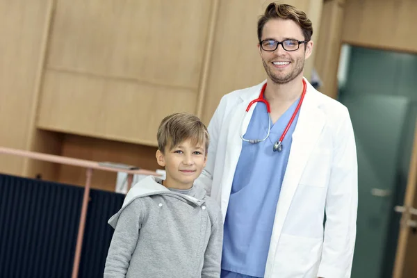 Médecin accueillant jeune garçon en clinique — Photo