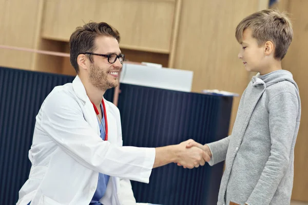 Médecin accueillant jeune garçon en clinique — Photo