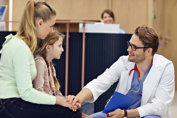 Doctor welcoming mother and daughter in clinic — Stock Photo, Image
