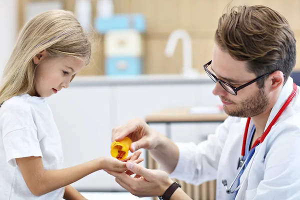 Male doctor giving pills to little girl — Stock Photo, Image