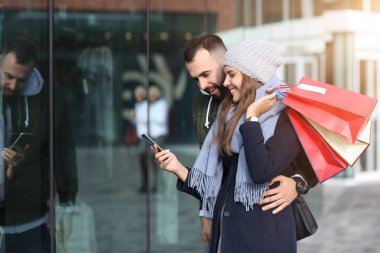 Alışveriş yaptıktan sonra alışveriş torbalarıyla mutlu bir çiftin portresi.
