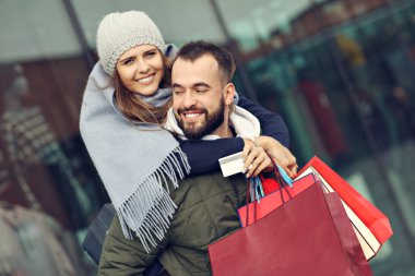 Alışveriş yaptıktan sonra alışveriş torbalarıyla mutlu bir çiftin portresi.