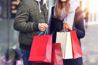 Alışveriş yaptıktan sonra alışveriş torbalarıyla mutlu bir çiftin portresi.