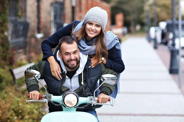 Hermosa pareja joven sonriendo mientras monta scooter en la ciudad en otoño — Foto de Stock