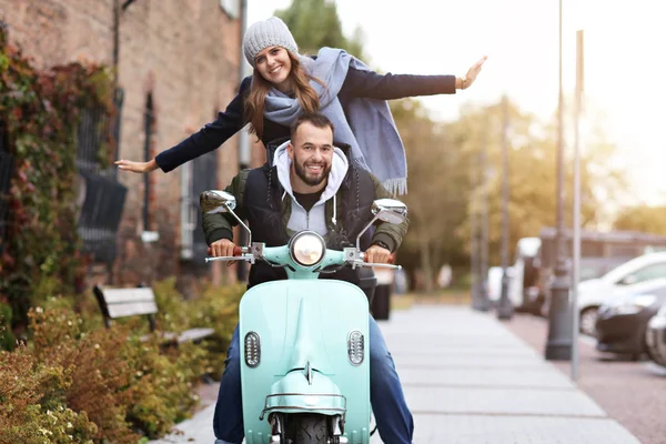 Mooie jonge paar glimlachen tijdens het rijden van scooter in stad in de herfst — Stockfoto