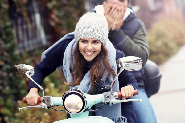 Hermosa pareja joven sonriendo mientras monta scooter en la ciudad en otoño — Foto de Stock