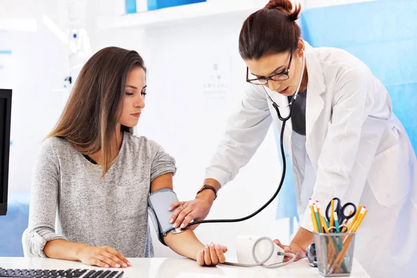 Donna adulta sottoposta a test della pressione sanguigna durante la visita presso lo studio medico femminile — Foto Stock