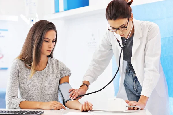 Mujer adulta que se somete a prueba de presión arterial durante su visita al consultorio — Foto de Stock