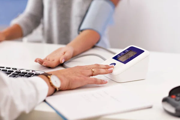 Mulher adulta tendo teste de pressão arterial durante a visita ao consultório médico feminino — Fotografia de Stock