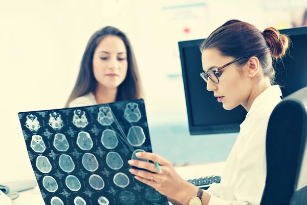 Adult woman discussing x-ray results during visit at female doctors office — Stock Photo, Image